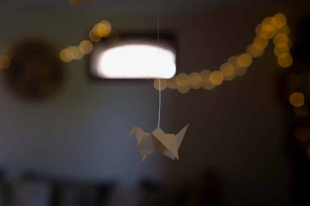 Grue en papier en gros plan avec guirlande lumineuse flou en arrière-plan